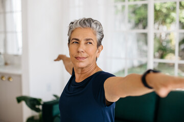 Senior woman stretching her arms in powerful warrior yoga pose