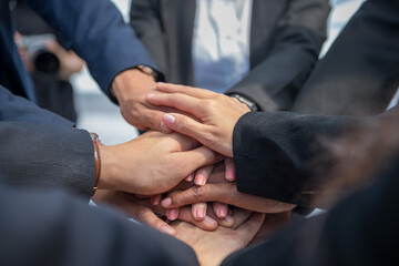business people putting join hands together. Unity and teamwork show by Stack mix of hands with...