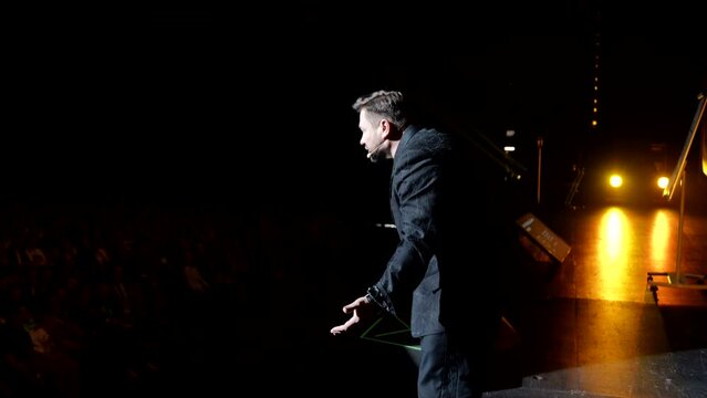 life coach on stage, charismatic man speaking emotionally, modern personal growth coaching