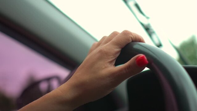Side view of woman hands on steering wheel driving vehicle on road. Adult girl having safety ride to job in vehicle