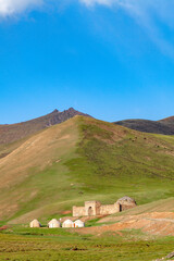 Landscape on the Silk Road with an ancient caravanserai and yurts in the pastures of Kyrgyzstan