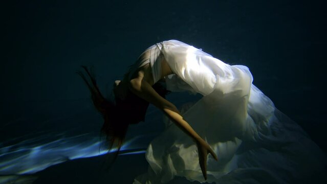 Plunging girl to fall under water Slow motion. Girl swimming under water in basin. Woman dives in the pool.