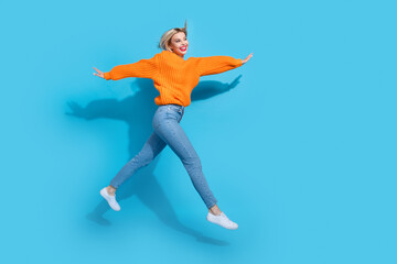 Fototapeta na wymiar Full body profile photo of cheerful pretty lady arms wings jump run empty space isolated on blue color background