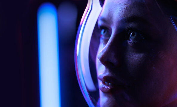 Astronaut in futuristic costume. Girl in glasses of virtual reality while touching air. Augmented reality game, future technology, AI concept. Dark background.