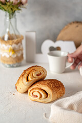 un pan con arequipe y queso rollo sobre otro pan en una mesa blanca con tematiac de una pasteleria 