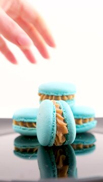 A girl lays out blue and pink macaroons to take a photo on grey background. Macaroons on grey background, colorful french cookies macaroons. Creative layout made of colorful macaroons. Food