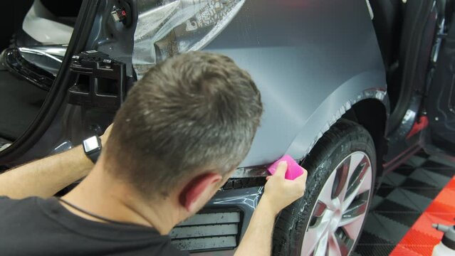 Process of applying a protective PPF film to a car. worker applying a protective film on a car. Closeup view shot