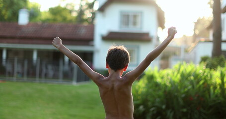 Kid raising arms in the air. Young boy child in victory stand raises fist outside