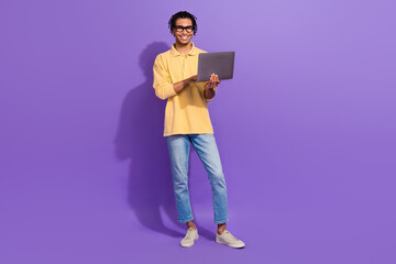 Full size body photo of young positive man sitting man using netbook first interview manager work guy isolated on purple color background © deagreez