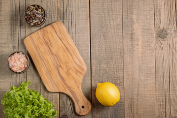 Wooden Cutting Board with Fresh Herbs and Raw Vegetables on Rustic Wood Table. Top view. Cooking...