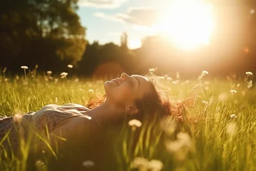 Fotobehang Weide Cheerful young woman smiling and enjoying in the sunset. Woman lying on the grass young woman laying in a field of bluebonnet wildflowers