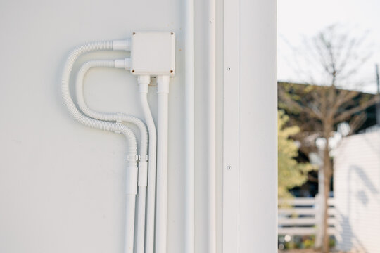 Professional outdoor electrical wiring wall installation with PVC conduit and waterproof connector box.