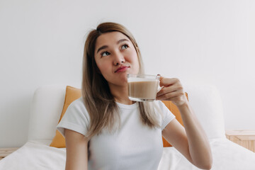 Happy Asian Thai woman holding coffee milk thinking something.