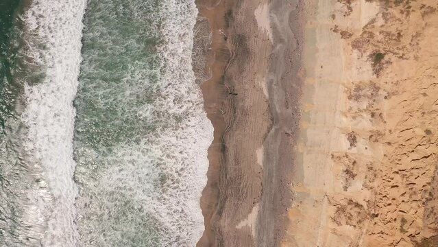Aerial birdseye footage of the ocean waves and sandy beach at La Jolla Shores taken during the day in the afternoon