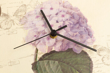 Agujas de un reloj en primer plano sobre un fondo de madera con una flor. Vista superior y de...