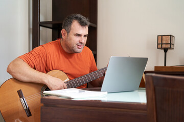 Fototapeta na wymiar a man with laptop in online guitar lessons learning harmonics