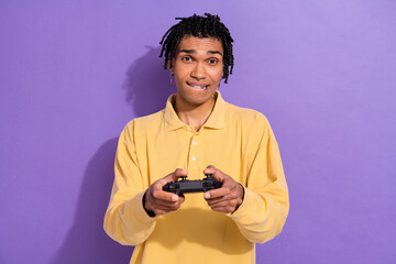Photo of excited cool person with cornrows wear yellow shirt biting lips hold playstation joystick...