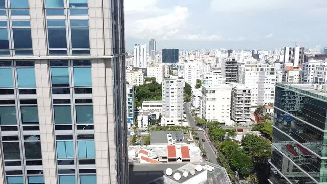 Drone vuelan por encima de la calle entre edificios modernos de altura con fachadas de color. Santo Domingo, Republica Dominicana, 2023