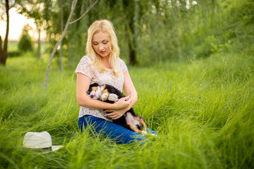 A beautiful girl with a Bernese Mountain Dog puppy is playing in nature. Love for dogs. Animal protection concept. Pet on a walk