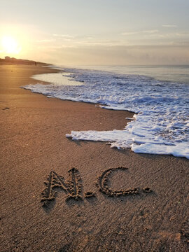 NC written in the sand at sunrise on the beach at Oak Island North Carolina