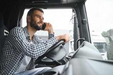 Young professional driver communicating over mobile phone while driving a truck
