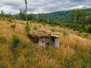 Plain with forest and abandoned concrete bunker in mountain. Jeseniky, Czechia.