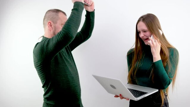 fooling around hitting on head with a tablet with a laptop girl talking on the phone laughing holding a laptop man hitting her on the head with a tablet joke funny behavior offending. abuser