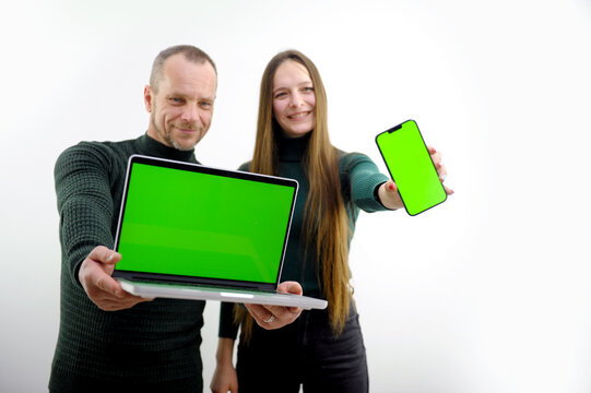 man and woman in hands with laptop and phone green screen chroma key space for text on white background cheerful happy faces good choice sale advertising. product offer to extend arms forward