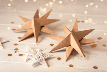 Paper Christmas stars on white wooden table. Front view.