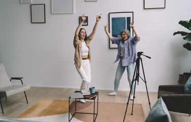 Cheerful mother and daughter dancing with hands raised - obrazy, fototapety, plakaty