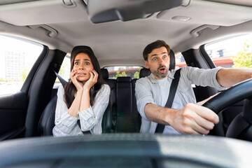 Shocked couple in automobile looking at road with shocked faces - obrazy, fototapety, plakaty