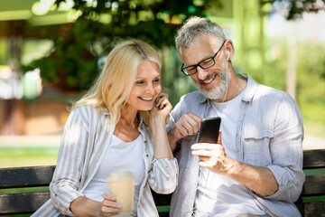 Romantic Mature Spouses Listening Music On Smartphone While Relaxing In Park