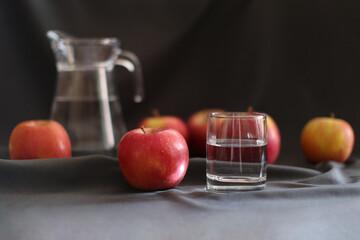 still life, a glass of water and ripe apples, a decanter in the background