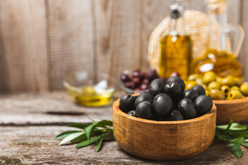 Set of black and green olives on a white wooden background. Various types of olives in wooden bowls and fresh olive leaves. Copy space. Place for text. flat lei. Delicatessen.