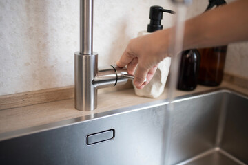 woman's hand turning off the water in the kitchen to avoid wasting water. energy savings against climate change