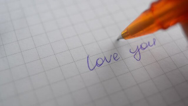 a man writes I love you on paper with a pen.