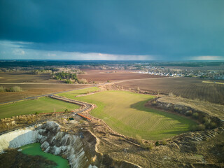 A dark thundercloud is moving over a rural field. A cloud with a clearly visible rain line. Aerial...