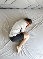 Overhead view of unhappy depressed young woman lying on bed in bedroom, suffering from depression, upset, suffering from emotional breakdown or crisis, healthcare concept