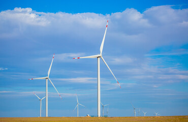 Fleet of power generators in motion. The blades of the wind farm rotate against the sky. The concept of extracting electricity from renewable sources. Wind turbine to generate electricity.
