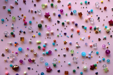 Various colorful beads on bright pink background. Top view.