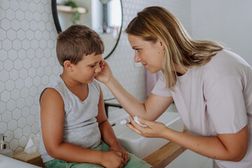 Mother checking her son's blood glucose level at home using a fingerstick glucose meter.