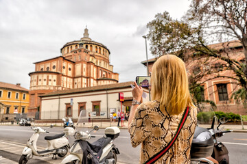 Milan, Italy - July 12, 2022: A woman taking pictures on the streets of Milan
