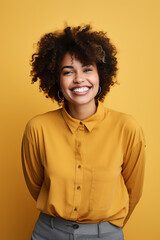 Fototapeta na wymiar Portrait of happy black woman looking at camera and smiling while standing on yellow background.