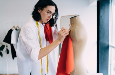 Focused craftswoman putting fabric on mannequin