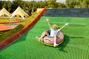 Happy boy descends in inflatable sledding tube on a summer track, having fun at amusement park....