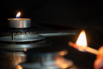 A lit match and a candle on a gas burner