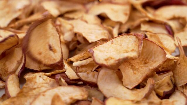 Sliced thin crispy apple chips falling in slow motion close up. Rotation