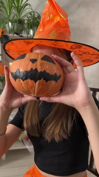 Children paint their faces and dress up. A girl in a witch costume for Halloween arranges a black scary party, Portrait of a girl for Halloween, vertical video