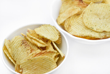 Yellow pieces of fried potatoes in a plate. Salted chips on a white background.