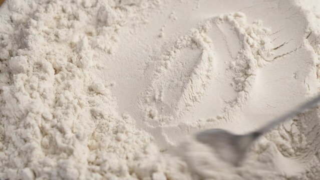 Pile of white wheat flour close up with spoon